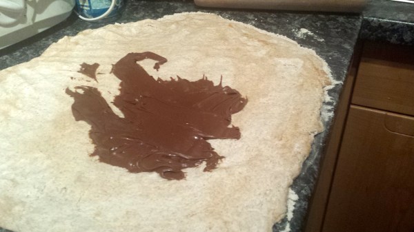 Nutella wird auf die Oberfläche des Teigs gestrichen.
